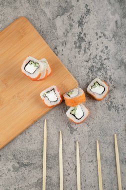 Taş zeminde taze somonla süslenmiş lezzetli suşi ruloları. Yüksek kalite fotoğraf