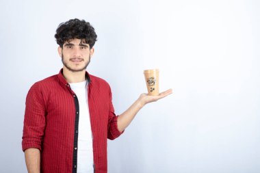 Beyaz arka planda duran bir fincan kahveyle genç bir adamın portresi. Yüksek kalite fotoğraf