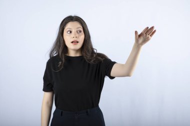 Siyah bluzlu esmer bir kızın beyaz duvarın üzerinden bir şeye baktığı görüntüsü. Yüksek kalite fotoğraf