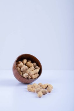 Beyaz arka planda soyulmamış fıstıklarla dolu ahşap bir kase. Yüksek kalite fotoğraf
