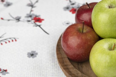 Tahta tabağa yerleştirilmiş kırmızı ve yeşil taze elma. Yüksek kalite fotoğraf