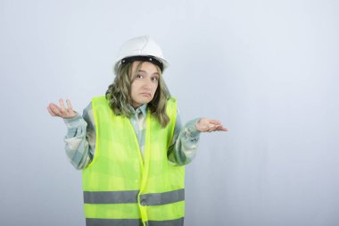 Beyaz fonda duran beyaz şapkalı genç inşaat işçisinin görüntüsü. Yüksek kalite fotoğraf