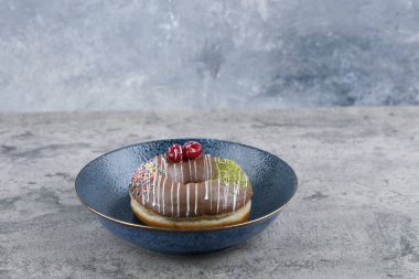 Çilekli çikolatalı donut ve mermer yüzeyine serpiştirilmiş mavi tabak. Yüksek kalite fotoğraf
