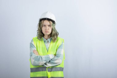 Beyaz fonda duran beyaz şapkalı genç inşaat işçisinin görüntüsü. Yüksek kalite fotoğraf