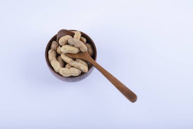 Ahşap kase dolusu soyulmamış fıstık ve beyaz arka planda kaşık. Yüksek kalite fotoğraf