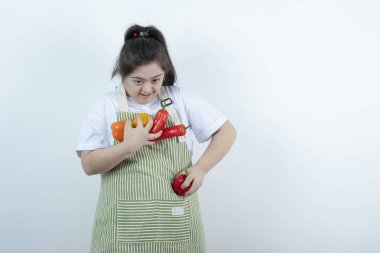 Kareli önlüğün içinde duran ve cebine sebze koyan genç ve güzel bir kız. Yüksek kalite fotoğraf
