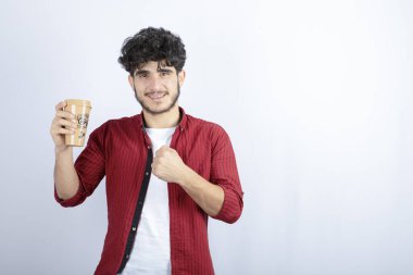 Beyaz duvarda mola vermek için elinde kahve tutan esmer adamın fotoğrafı. Yüksek kalite fotoğraf