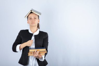 Kafasında bir sürü kitap olan güzel bir öğretmenin resmi. Yüksek kalite fotoğraf