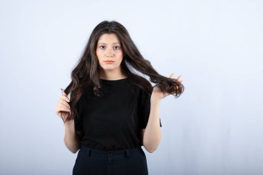 Siyah bluzlu esmer bir kızın beyaz duvardan kameraya baktığı görüntü. Yüksek kalite fotoğraf