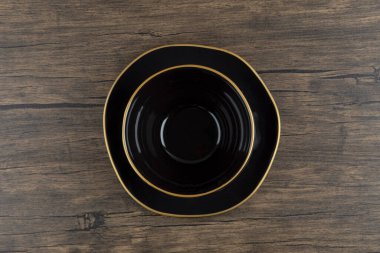 Ahşap yüzeyde siyah boş çorba kasesi ve tabak. Yüksek kalite fotoğraf