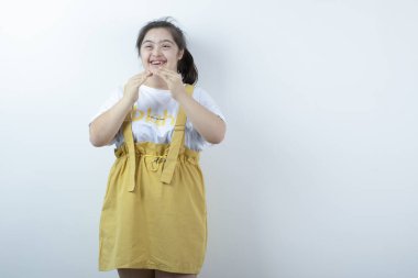 Beyaz duvarın karşısında duran ve gülümseyen genç, güzel kız modeli. Yüksek kalite fotoğraf