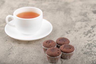 Taş bir masanın üzerine çikolatalı kek konmuş beyaz bir fincan sıcak çay. Yüksek kalite fotoğraf