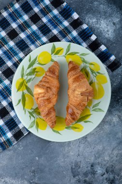 Mermer bir arka plana yerleştirilmiş renkli bir tabak taze kruvasan. Yüksek kalite fotoğraf