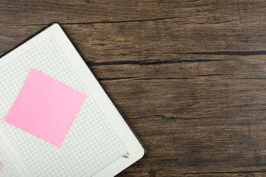 Ahşap arka planda not defteri olan pembe kare çıkartma. Yüksek kalite fotoğraf