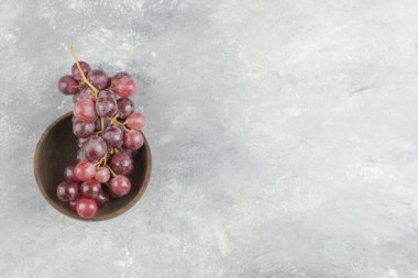 Mermer yüzey üzerinde ahşap bir kase taze kırmızı üzüm. Yüksek kalite fotoğraf