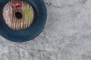 Çilekli çikolatalı donut ve mermer yüzeyine serpiştirilmiş mavi tabak. Yüksek kalite fotoğraf