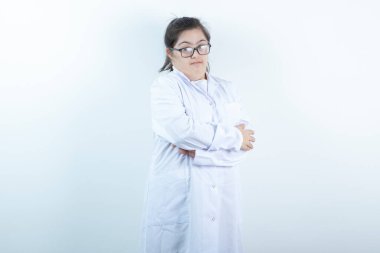 Doktor üniformalı genç bir kız kollarını kavuşturmuş duruyor. Yüksek kalite fotoğraf