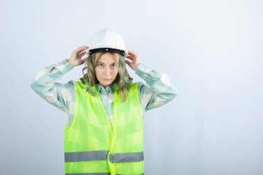 Beyaz arka planda duran yeşil yelekli genç inşaat işçisinin fotoğrafı. Yüksek kalite fotoğraf