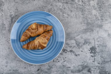 Taş yüzeyde mavi bir tabak taze çikolatalı kruvasan. Yüksek kalite fotoğraf