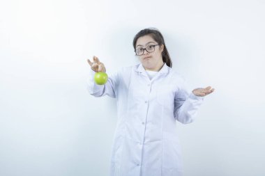 Elinde yeşil elma tutan doktor üniformalı genç bir kız. Yüksek kalite fotoğraf