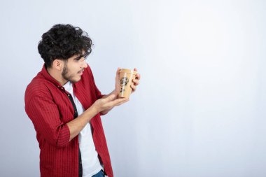 Beyaz arka planda bir fincan kahveye bakan genç bir adam resmi. Yüksek kalite fotoğraf