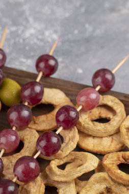 Kurutulmuş elma halkaları, kırmızı üzümler ve ahşap tabakta kumkatlar. Yüksek kalite fotoğraf
