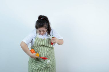 Kareli önlüğün içinde duran ve cebine sebze koyan genç ve güzel bir kız. Yüksek kalite fotoğraf