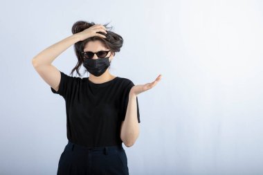 Beyaz arka plandaki salgın nedeniyle genç bir kızın portresi siyah bir maske takıyor. Yüksek kalite fotoğraf