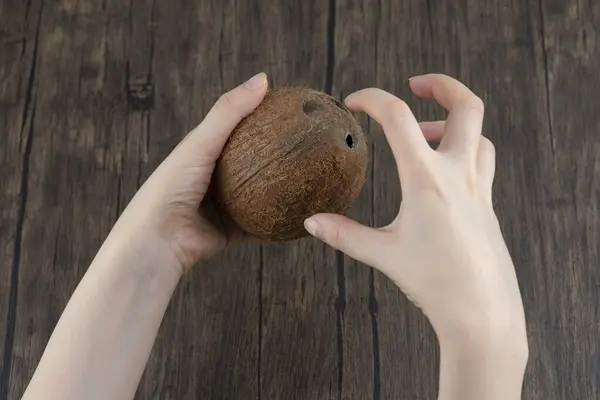 Vrouwelijke Handen Met Rijpe Hele Kokosnoot Een Houten Tafel Hoge — Stockfoto