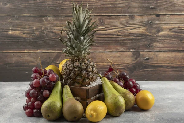 Tahta kutuda olgun ananas ve mermer yüzeyinde çeşitli taze meyveler. Yüksek kalite fotoğraf
