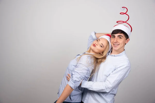 Gri Arka Planda Noel Baba Şapkalarıyla Poz Veren Sevimli Genç — Stok fotoğraf