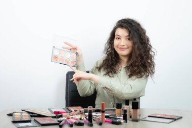 Makyaj malzemeleriyle masada oturan genç bir kadın. Yüksek kalite fotoğraf