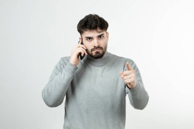 Akıllı telefonda beyaz duvara karşı konuşan çekici adamın portresi. Yüksek kalite fotoğraf