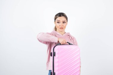 Elinde bavul tutan pembe kapüşonlu çekici bir kadın resmi. Yüksek kalite fotoğraf