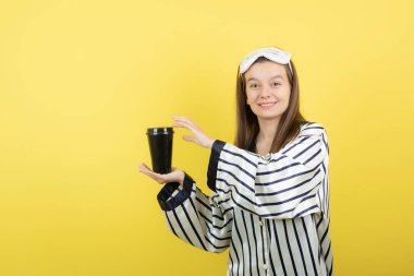 Pijama giyen ve elinde bir fincan sıcak çay tutan güzel genç bir kadın. Yüksek kalite fotoğraf