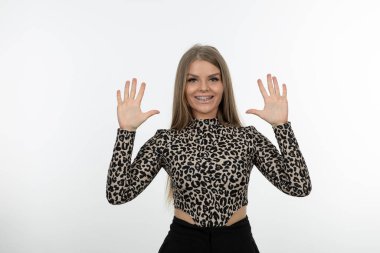 Gülümseyen ve avuçlarını beyaz duvara doğru açan güzel bir kadın. Yüksek kalite fotoğraf