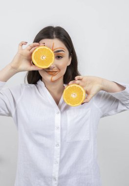 Sarı gözlü, turuncu saçlı, elinde kivi ve kafasında limon tutan güzel bir kadın.