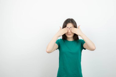 Genç ve güzel bir kadın modelin ayakta ve elleri ile gözleri kapladığı görüntüsü. Yüksek kalite fotoğraf