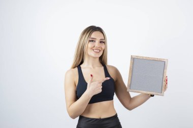 Beyaz arka planda boş bir tahtası olan güzel genç bir kadın.