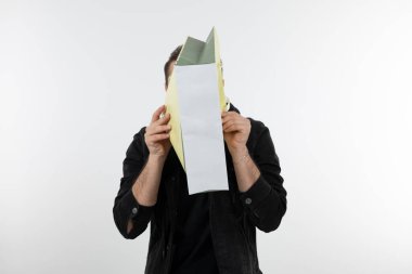 Beyaz bir duvarın üzerinde alışveriş torbası tutan genç yakışıklı bir adam. Yüksek kalite fotoğraf