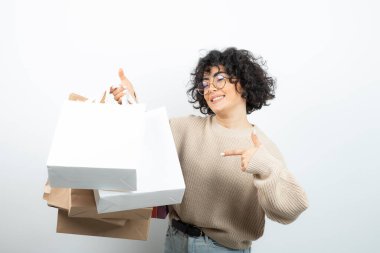 Alışveriş torbalarıyla ayakta poz veren genç bir bayan. Yüksek kalite fotoğraf