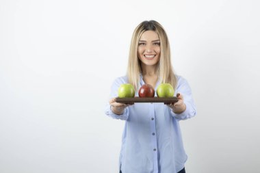 Tahtada yeşil ve kırmızı elmalar tutan sarışın bir kızın portresi. Yüksek kalite fotoğraf