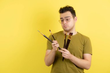 Elinde fırça tutan yakışıklı bir erkek ressam resmi. Yüksek kalite fotoğraf