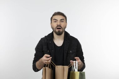 Beyaz bir duvarın üzerinde alışveriş torbaları tutan genç yakışıklı bir adam. Yüksek kalite fotoğraf