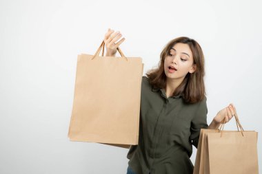 Beyazların üzerinde duran el işi çantaları olan genç bir manken resmi. Yüksek kalite fotoğraf