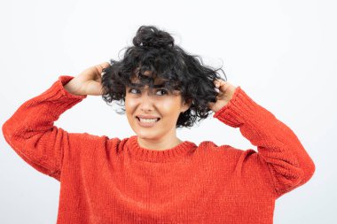 Kırmızı kazaklı, kısa saçlı kıvırcık bir kızın bir yerlere baktığı görüntüsü. Yüksek kalite fotoğraf