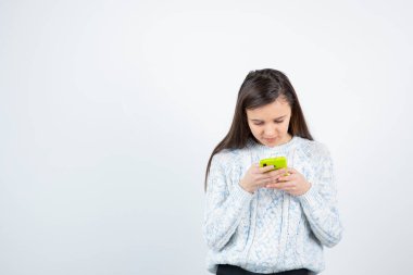 Beyaz arka planda duran süveter giyen kız