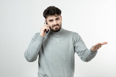 Akıllı telefonda beyaz duvara karşı konuşan çekici adamın portresi. Yüksek kalite fotoğraf