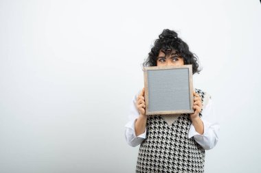 Genç esmer kız beyaz çerçevenin arkasında saklanıyor. Yüksek kalite fotoğraf