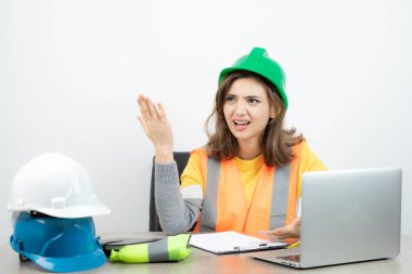Masada dizüstü bilgisayarı ve not panosuyla oturan üniformalı bir kadın. Yüksek kalite fotoğraf